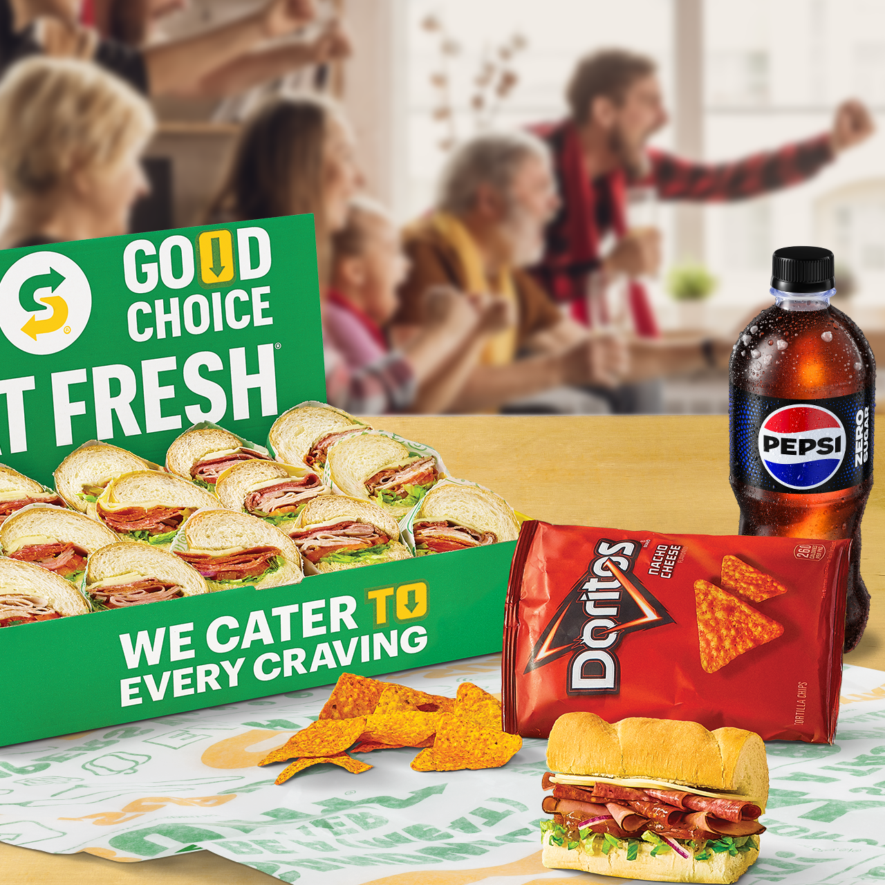 Plato de Subway® Catering con Ultimate B.M.T.®, Doritos y una botella de Pepsi mientras los fanáticos del fútbol animan de fondo